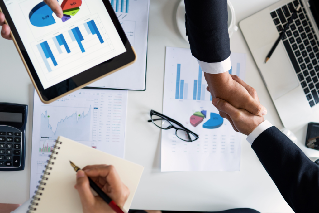 Business handshake over financial reports and graphs